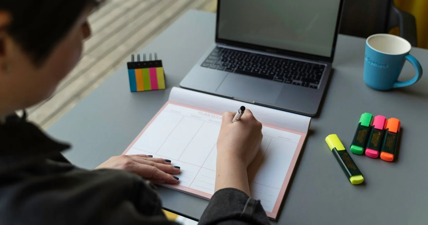 Person writing three priorities in a planner at a desk